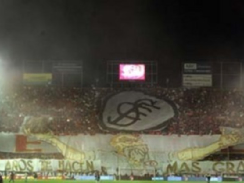 Estadio lleno de aficionados con una gran bandera que dice "Los años no hacen más grande".