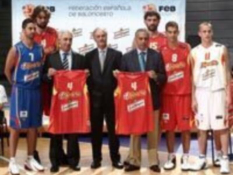 Un grupo de personas, entre ellos jugadores de baloncesto y un hombre con corbata, sostienen trofeos en una ceremonia. El ambiente es formal y festivo, reflejando el éxito de un equipo en competiciones deportivas.