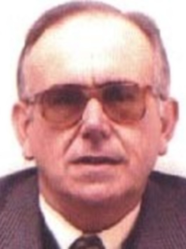 Este es un retrato de una persona con cabello blanco y barba, vistiendo una camisa blanca. La imagen parece ser de un individuo adulto con expresión seria y mirada directa hacia la cámara.