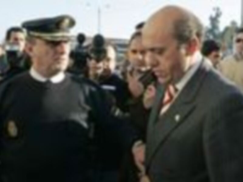 Dos hombres en uniforme militar y otro en traje formal, posiblemente en un evento oficial o ceremonia.