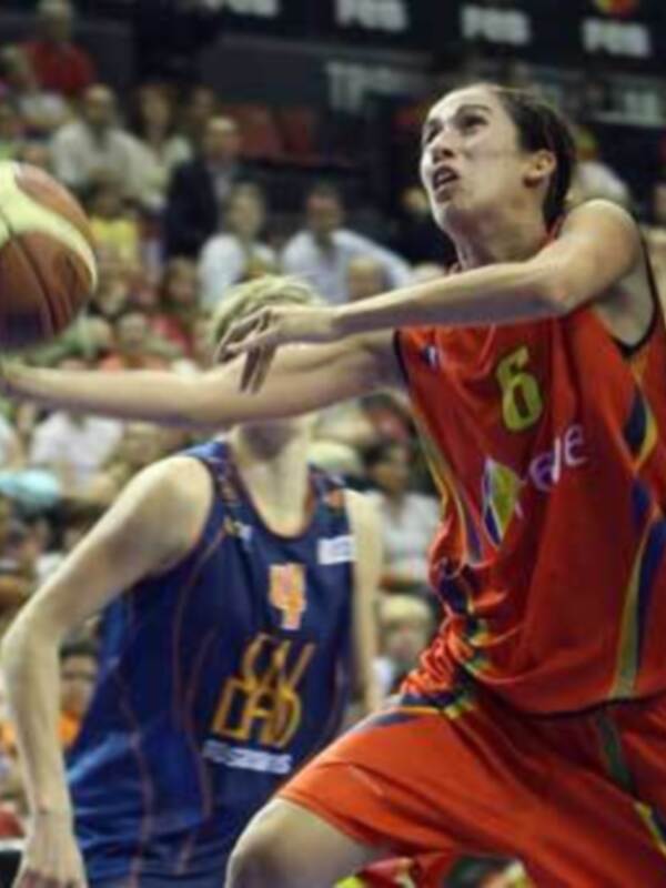 Una jugadora española de baloncesto en acción, con el número 6 en su camiseta, luchando por el balón frente a una jugadora de la selección española rival. El escenario es un estadio lleno de espectadores.