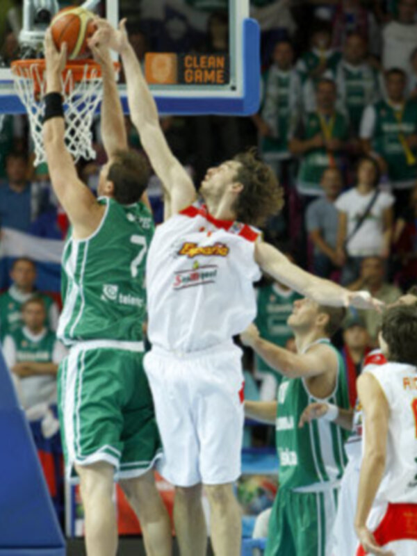 Jugadores en acción durante un partido de baloncesto en FIBA Europe, con un jugador en blanco intentando marcar mientras otro en verde intenta bloquear.