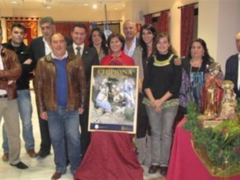 Grupo de personas posando con un cartel y una imagen de la Virgen María en un evento navideño.