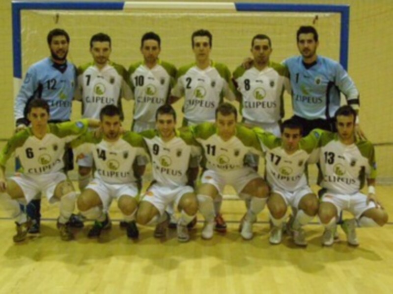 Equipo de fútbol sala posando para una foto de equipo en una cancha de madera.
