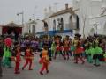 Desfile de carnaval en un pueblo andaluz, con disfraces coloridos y figuras gigantes.