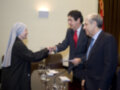 Two individuals in a formal setting, one dressed in a nun's habit shaking hands with another in a suit.