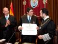 Entrega de un certificado en una ceremonia oficial con uniformes judiciales y banderas.