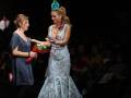 Modela recibiendo flores de una invitada en un desfile de moda.