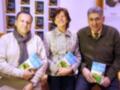 Tres personas sonrientes sostienen libros en una librería llamada Casa del Libro.