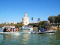 Puerto de Sevilla con el Torre del Oro al fondo. Barcos navegando en el río Guadalquivir.