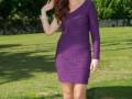 Elegante mujer con vestido morado en un parque soleado.