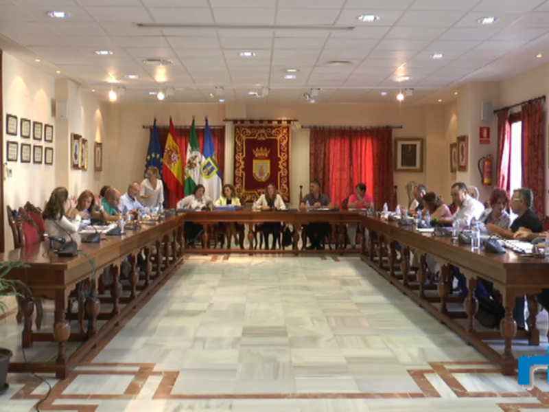Una sala de conferencias con un largo comedor rodeado por sillas y mesas. En la pared, hay varias banderas y cuadros decorativos. La sala está iluminada con luces de techo y tiene un suelo de mármol.