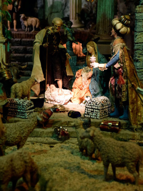 Escena de Navidad con figuras religiosas y animales en un entorno decorativo.