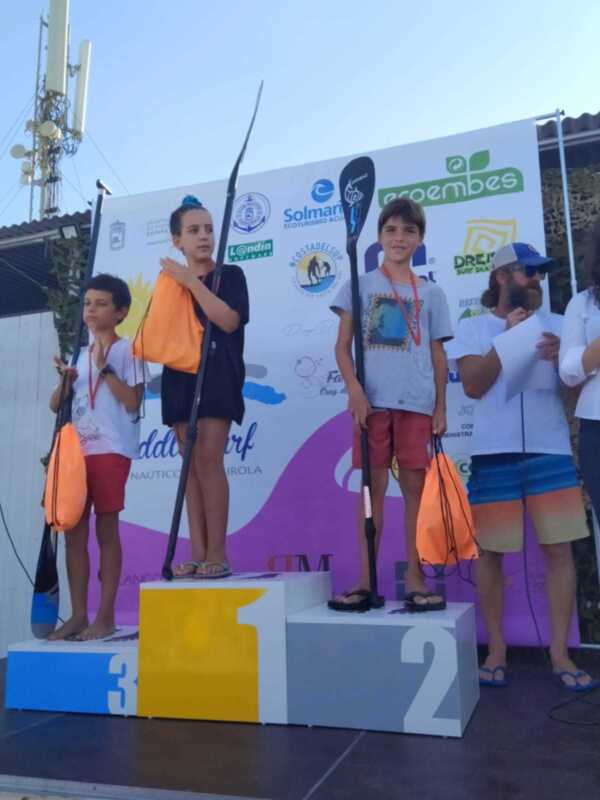Un niño en segundo lugar sostiene una bandera mientras otros niños celebran en el podio.
