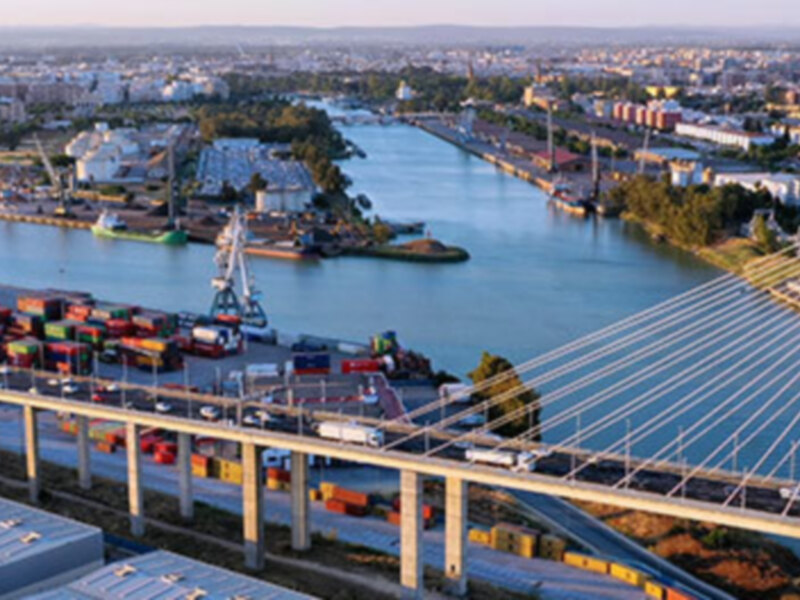 Puente de cables y contenedores de carga en el puerto fluvial de Sevilla, España.