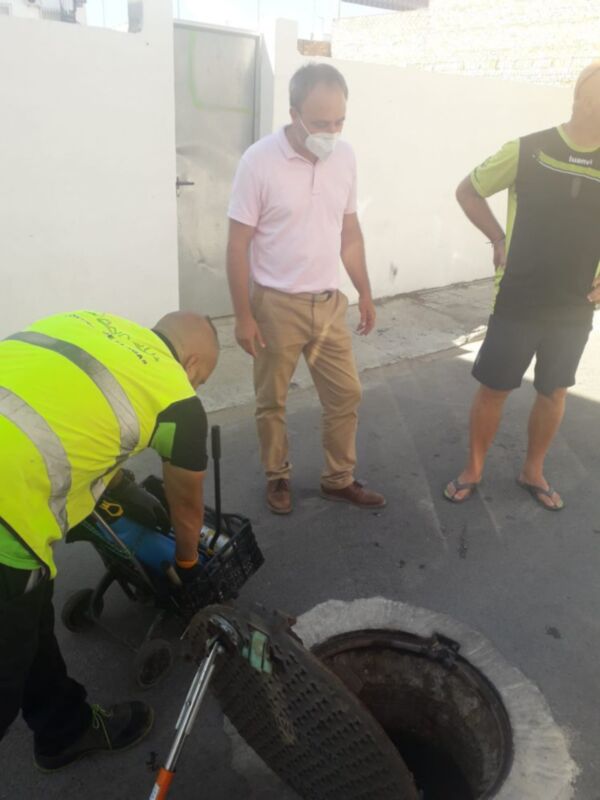 Trabajadores inspeccionando una alcantarilla en una calle de la ciudad.