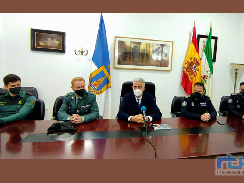Un grupo de personas en uniforme militar se reúnen alrededor de una mesa con banderas y un mapa en el fondo. La imagen parece ser de un evento oficial o conferencia informativa.