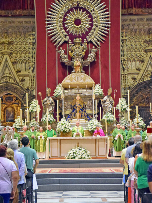 Eucaristía en la Catedral de Sevilla, con la Virgen de la Macarena en el altar y fieles en oración.