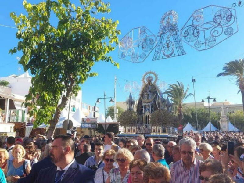 Fotografía de una multitud celebrando frente a un edificio religioso con decoraciones navideñas en el cielo.