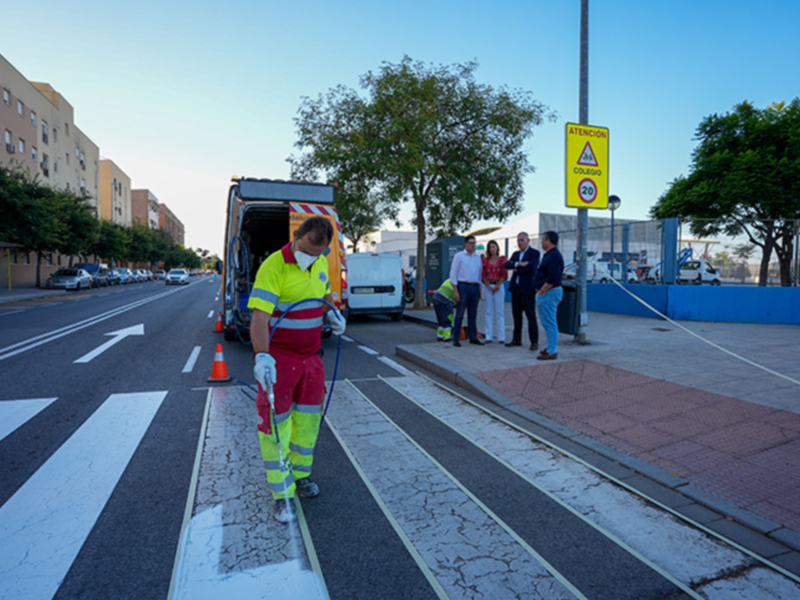 Trabajador de limpieza en un carril de la calle, con una camioneta de limpieza y personas observando.