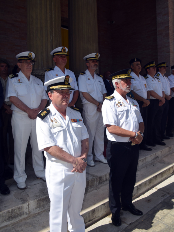 Un grupo de oficiales militares en uniforme blanco y gorras de marinero, posando en una escalinata al aire libre con columnas de fondo.