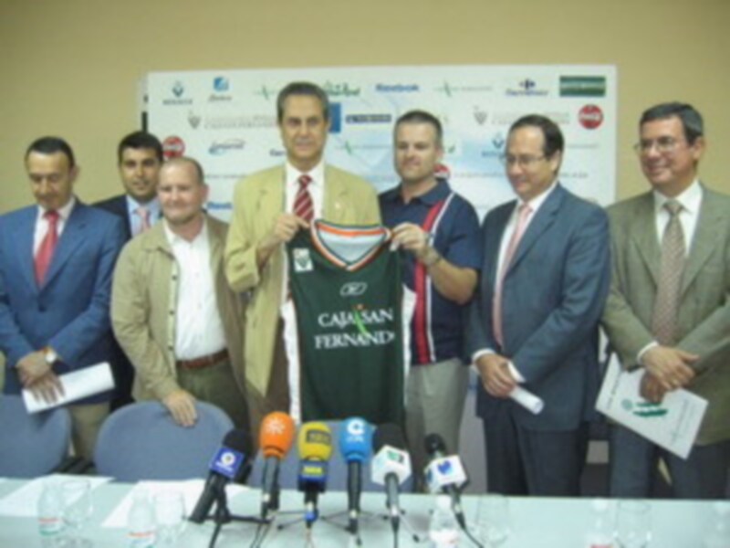 Un grupo de hombres en una conferencia de prensa, posando con un jersey de fútbol y sosteniendo folletos. En el fondo, se ven varios logotipos de patrocinadores.