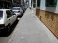 Calle con coches aparcados y una pared amarilla con un garaje.