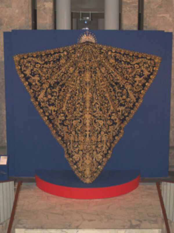 Un tapiz con un diseño floral dorado sobre un fondo azul, expuesto en un museo.