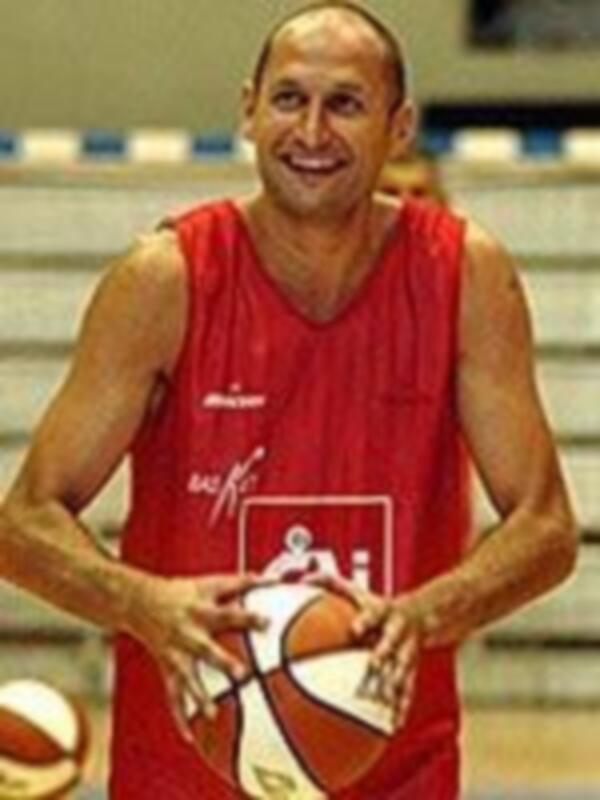 Un hombre en una camiseta roja con un balón de baloncesto, posiblemente en un entrenamiento o partido de baloncesto.