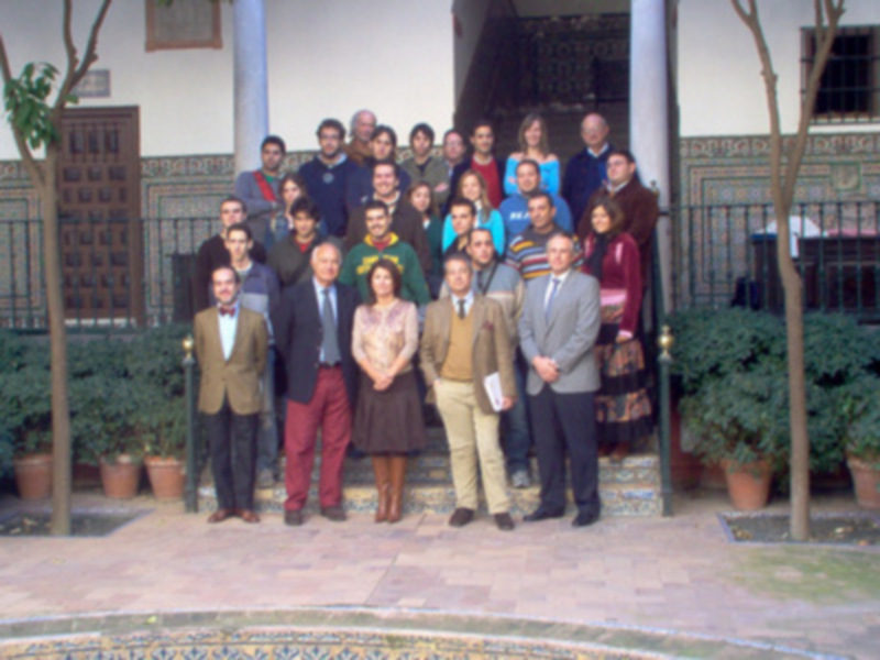 Grupo de personas posando en una fachada con azulejos y plantas.