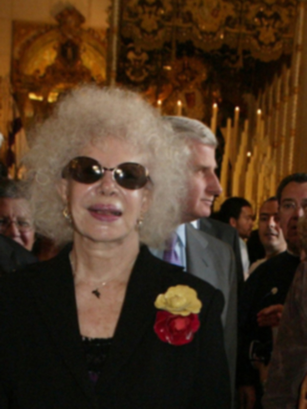 Una mujer con cabello blanco y gafas de sol, posando para la cámara en un evento formal.