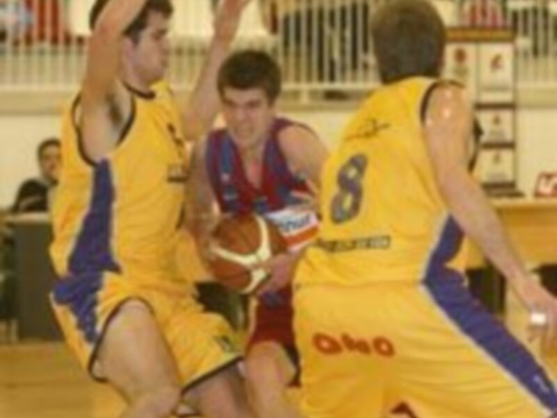 Jugadores de baloncesto en acción durante un partido. El jugador del equipo amarillo con el número 8 está en movimiento, mientras que los jugadores de la otra equipación intentan interceptar el balón.
