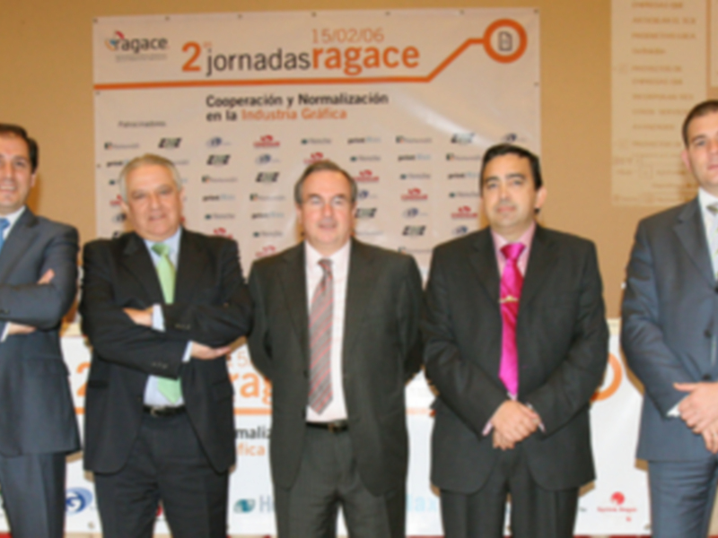 Cuatro hombres en trajes posan frente a un cartel con el logo de Agace y el texto '2 jornadas Agace'.
