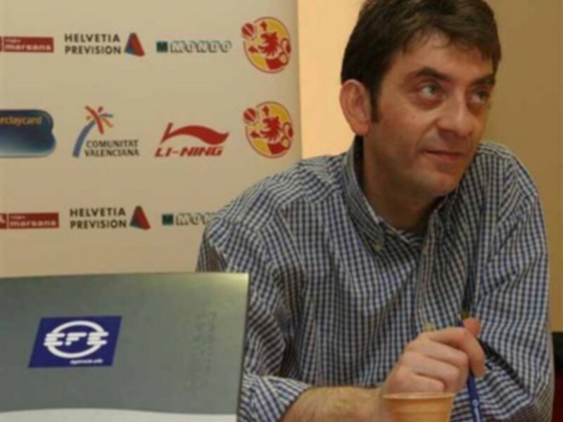 Un hombre en una conferencia de prensa, con una camisa a cuadros y un marcador en la mano. El fondo muestra logos de diferentes empresas, incluyendo Helvetia, Li-Ning y EFS.