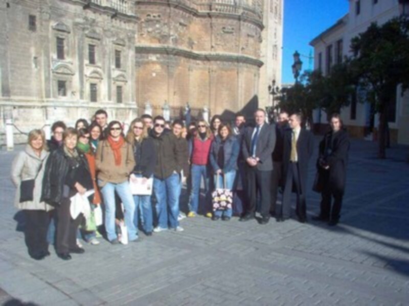 Gente posando frente a un edificio histórico con una torre en el centro.