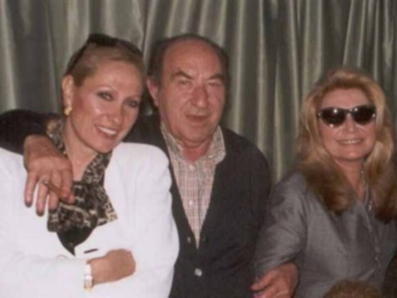 Tres personas posando juntas, una mujer con gafas de sol y un hombre en medio.