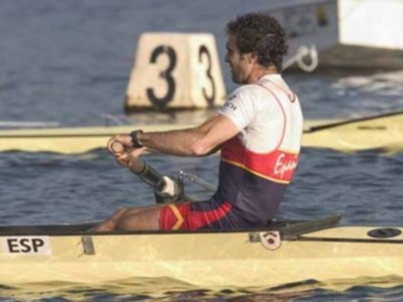 Un hombre en una canoa de remo, con el número 3 visible detrás de él. La canoa tiene la bandera española y el nombre 'Eguren' en la parte superior. El agua es azul y parece ser un día soleado.
