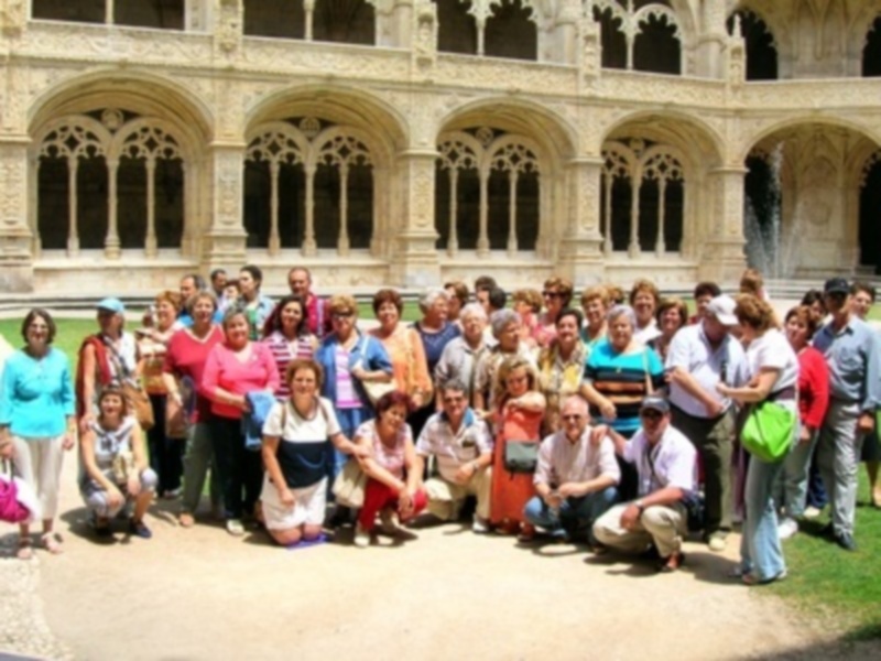 Grupo de personas posando frente a un edificio histórico con arcos y columnas.