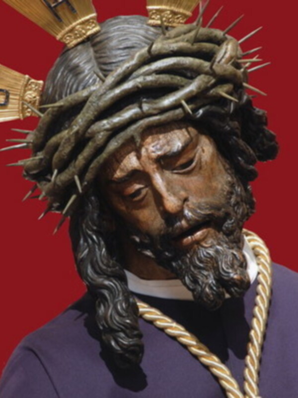 Cabeza de un personaje con corona de espinas y una cadena dorada, en un contexto religioso o histórico.