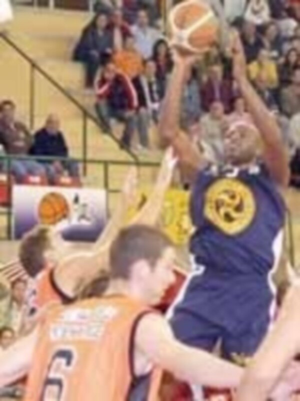 Jugador en acción durante un partido de baloncesto, luchando por el balón en el aro.