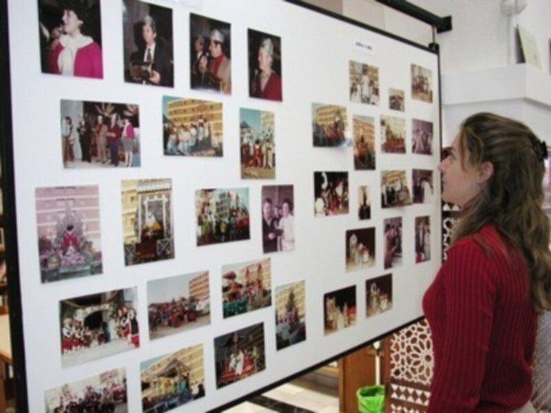 A una persona observando varias fotos colgadas en un panel. Las fotos representan diferentes escenas y eventos, posiblemente de una exposición o presentación. La persona está mirando atentamente la imagen, mostrando interés en el contenido visual.