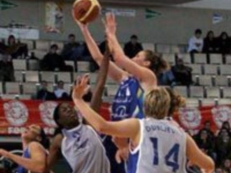 Un partido de baloncesto en un estadio con espectadores en las gradas, destacando a un jugador en acción con el número 14 en su camiseta.