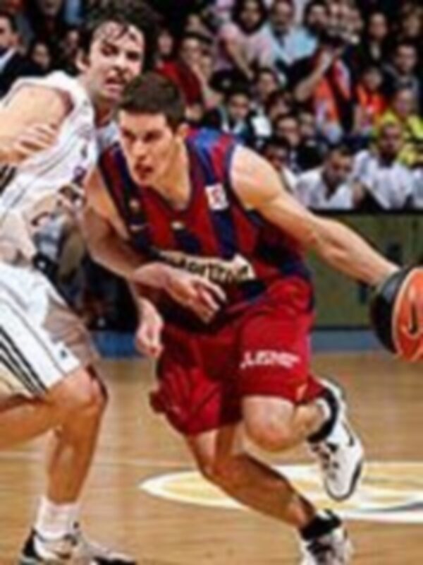 Un jugador de baloncesto en acción, con el balón bajo la mano, rodeado por otros jugadores en un partido de baloncesto.