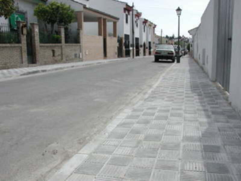 Calle vacía con casas blancas y verdes, una calle de adoquines.