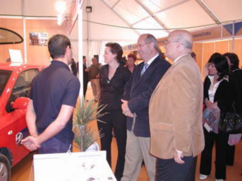 Exposición de vehículos eléctricos con visitantes intercambiando ideas.