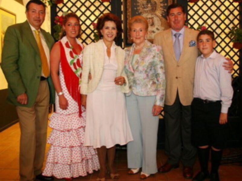 Una familia feliz en una reunión familiar, con una mujer en el centro, rodeada por sus padres y hermanos, todos sonrientes y felices.