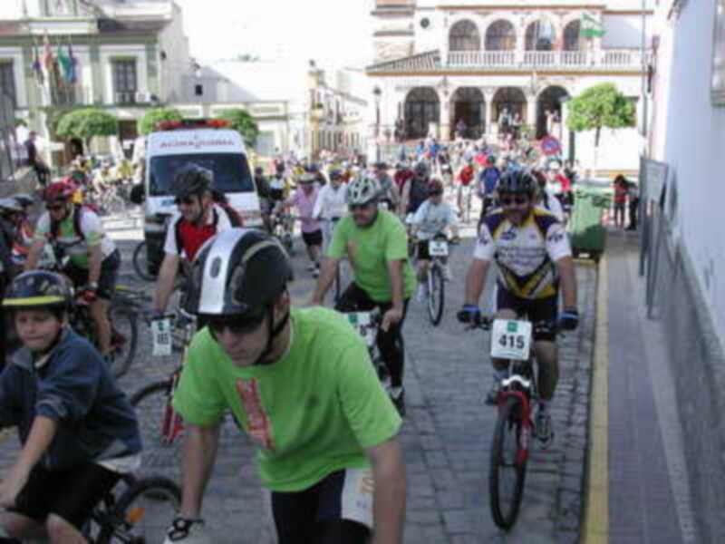 Ciclistas en una carrera urbana, con edificios históricos al fondo.