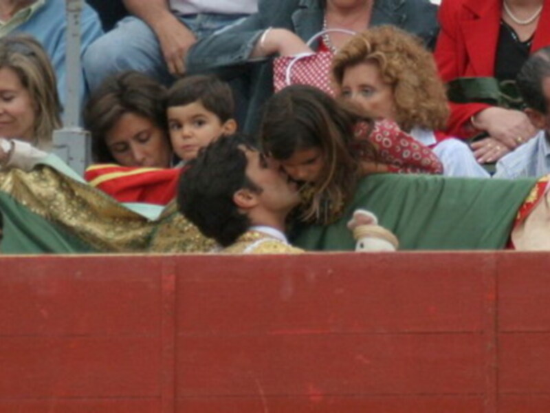 Una joven con un vestido rojo y blanco está besando a un niño en un ambiente festivo.