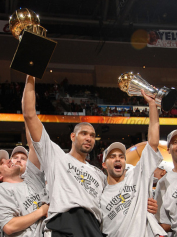 Un equipo de baloncesto celebra una victoria, sosteniendo un trofeo dorado en el centro de la imagen.