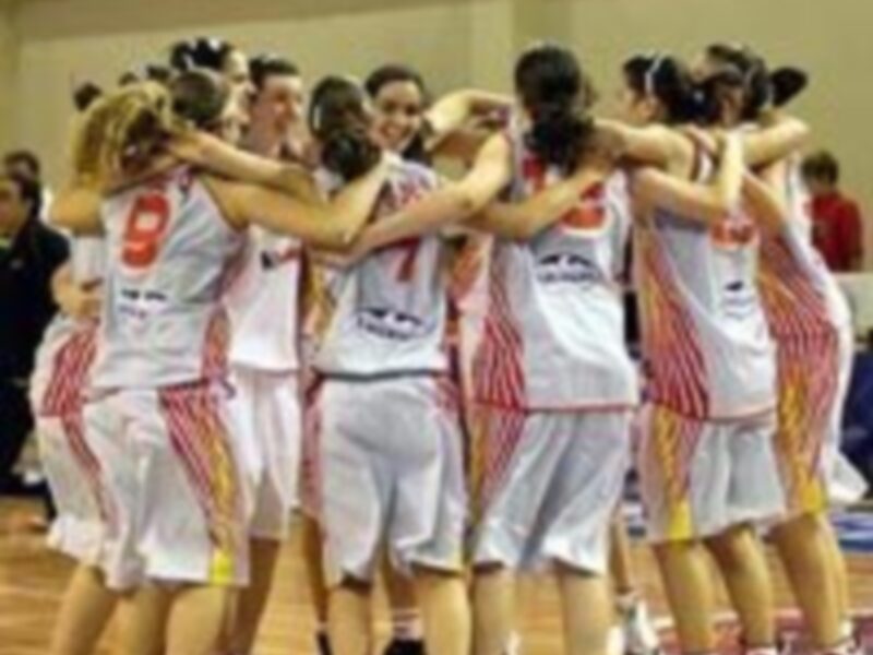 Equipo femenino de baloncesto celebrando un triunfo junto a su entrenador.